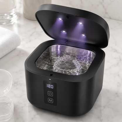 Black U-Brightwave ultrasonic cleaner with the lid open on a marble counter, showing a clear aligner tray in the water basin, with aligner cases nearby.